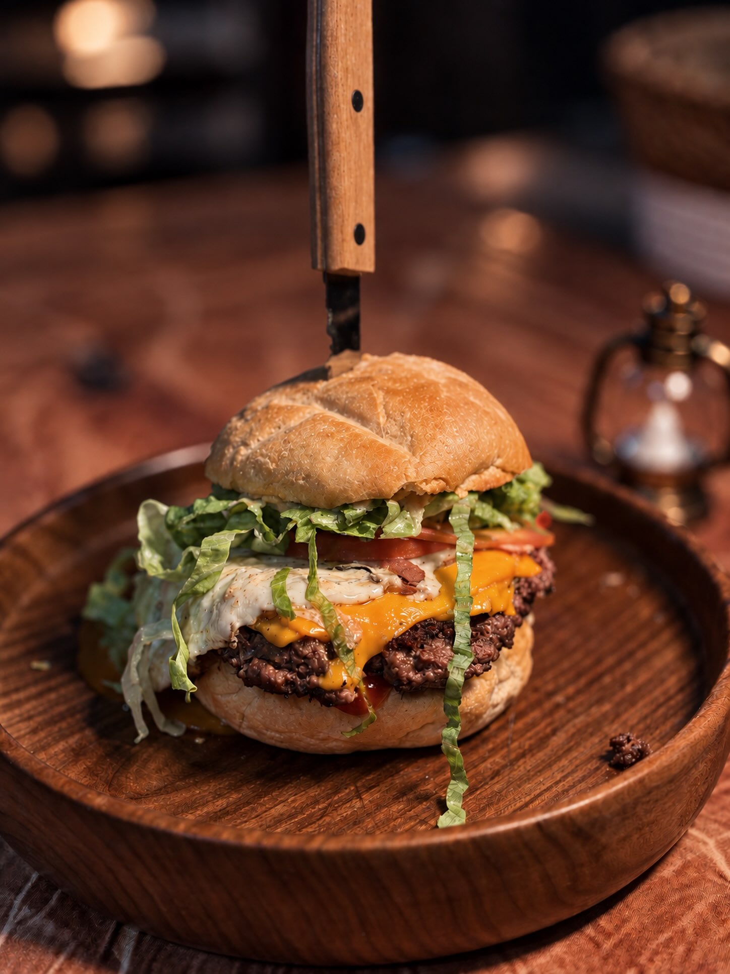 Hamburguesa de Forastero sobre tabla de madera, con queso, huevo y vegetales